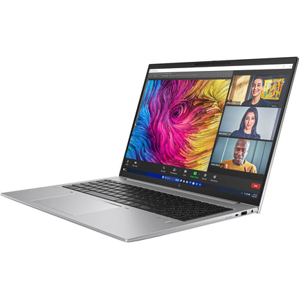 Angled view of a slim, silver refurbished HP ZBOOK FIREFLY 16 G11 laptop, featuring a 16” FHD display with a vibrant abstract wallpaper and an active video call displaying three people in a virtual meeting; the image highlights the screen, keyboard, and side ports. - View 4
